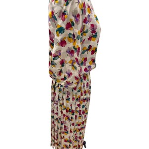 May include: A white dress with a floral print in shades of pink, yellow, green, and purple. The dress has a pleated skirt and a fitted bodice.