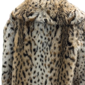 May include: A brown and white faux fur coat with a leopard print pattern. The coat has a large collar and is made of soft, plush fabric.