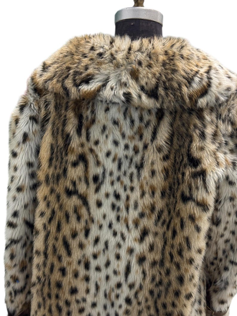May include: A brown and white faux fur coat with a leopard print pattern. The coat has a large collar and is made of soft, plush fabric.