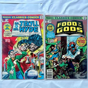 Puede incluir: Dos cómics vintage de Marvel Classics. El primero presenta "Dr. Jekyll y Mr. Hyde" con una portada roja y amarilla. El segundo cómic es "Food of the Gods" con una portada verde y roja. Ambos cómics están en fundas protectoras.