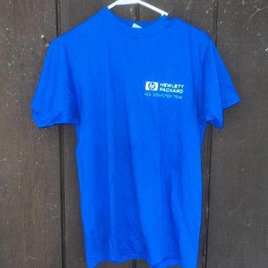 May include: A royal blue t-shirt with a white Hewlett Packard logo and the text "NEA Computer Team".