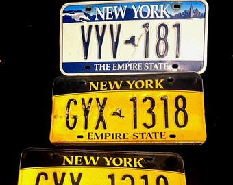 Three Vintage New York License Plates 1 White, two gold and blue Gold and Blue Empire, 1 New York Yellow Blue Font.  Real vintage NY Plates