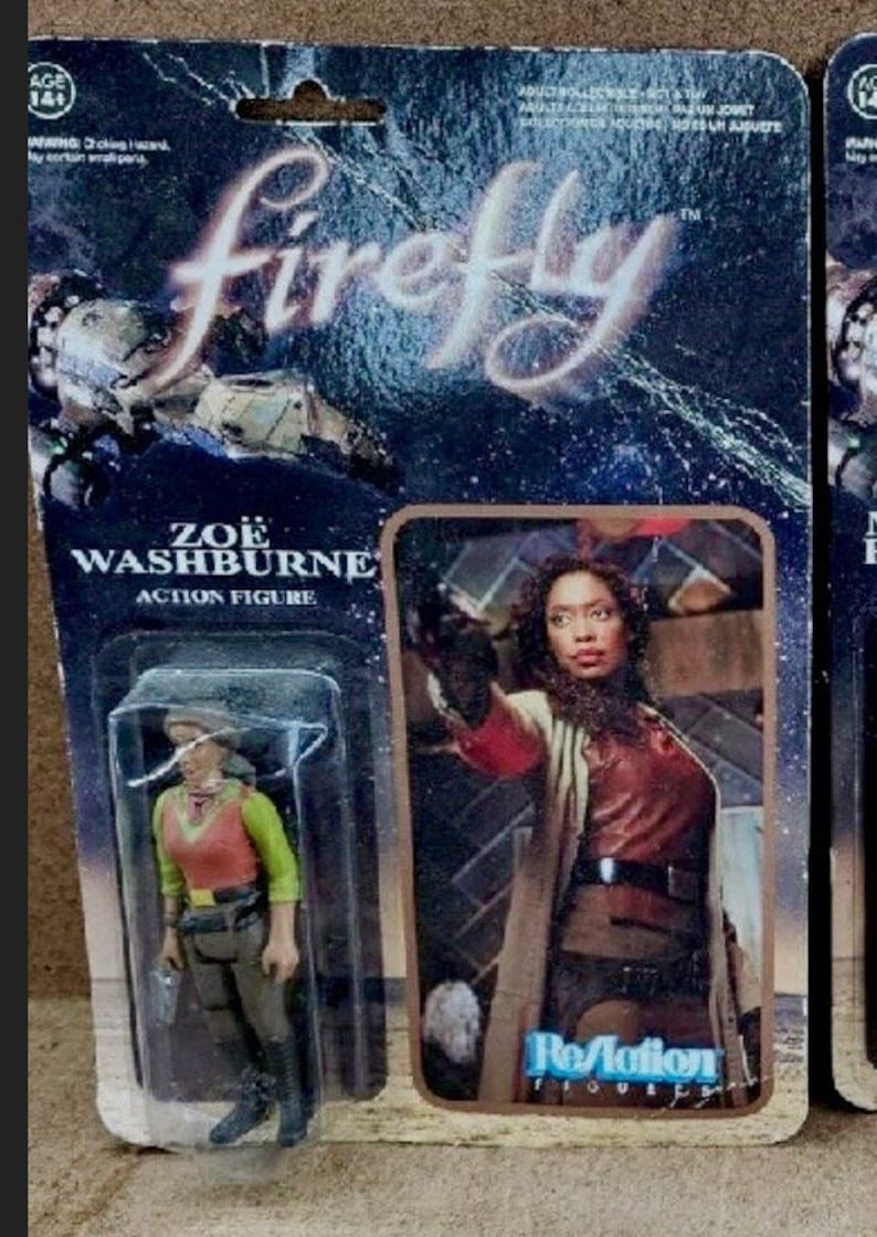 May include: A plastic action figure of Zoe Washburne from the TV show Firefly. The figure is packaged in a blister pack with a photo of Zoe holding a gun. The packaging is blue and black with the words "Firefly" and "ReAction" printed on it.