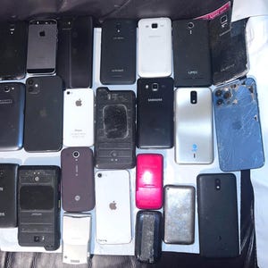 May include: A collection of various used smartphones, including models from Apple, Samsung, and Alcatel. The phones are in various conditions, with some showing signs of wear and tear. The image showcases a variety of colors and designs.