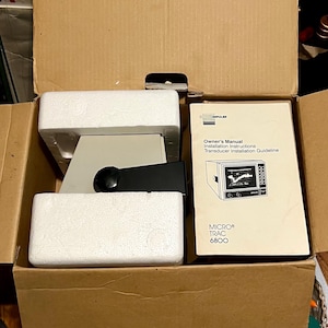 May include: A cardboard box containing a piece of electronic equipment secured with white styrofoam packaging. Next to the equipment is a manual titled Impulse Owner's Manual, Installation Instructions, Transducer Installation Guideline, MICRO TRAC 6800.