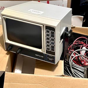 May include: An off-white Impulse Micro-Trac 6800 marine electronic display unit with a dark screen, black control knobs, and a vertical keypad. The device features a black mounting bracket and is accompanied by a bundle of red, black, and gray wires.