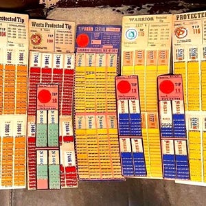 Può includere: Una collezione di carte da gioco in carta vintage con vari numeri di serie e valori. Le carte sono stampate in tonalità di giallo, arancione, rosso, blu e verde, con testo che include Werts Protected Tip, Warrior e Tip 115.