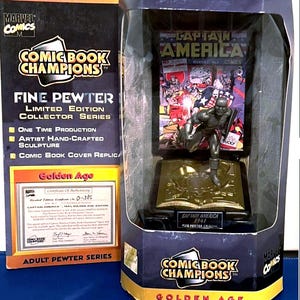 K&ouml;nnte beinhalten: Eine limitierte Captain America Figur aus feinem Zinn aus der Golden Age Serie, pr&auml;sentiert in einer Comic Book Champions Box. Die Figur ist eine handgefertigte Skulptur mit einer Comic-Cover-Replik. Die Box enth&auml;lt ein Echtheitszertifikat.