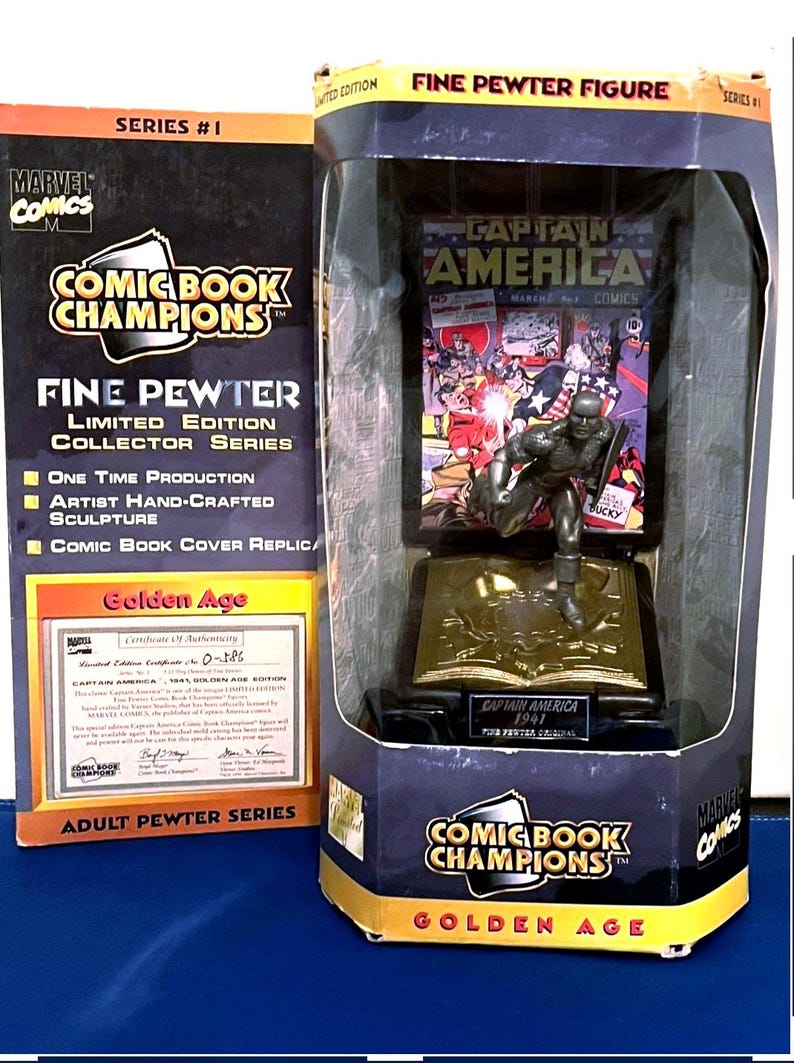 K&ouml;nnte beinhalten: Eine limitierte Captain America Figur aus feinem Zinn aus der Golden Age Serie, pr&auml;sentiert in einer Comic Book Champions Box. Die Figur ist eine handgefertigte Skulptur mit einer Comic-Cover-Replik. Die Box enth&auml;lt ein Echtheitszertifikat.