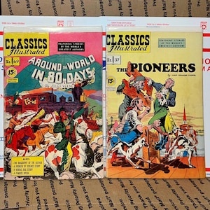 Puede incluir: Dos cómics vintage "Classics Illustrated". Uno presenta "La vuelta al mundo en 80 días" de Julio Verne, y el otro "The Pioneers" de James Fenimore Cooper. Ambos cómics tienen portadas coloridas con ilustraciones y texto.