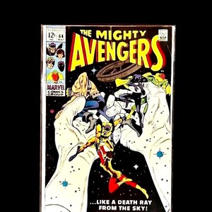 Puede incluir: Una portada de cómic vintage de "The Mighty Avengers" #64. La portada presenta una ilustración dinámica de varios superhéroes disfrazados en un entorno espacial, con el título en amarillo y rojo. El logotipo de Marvel Comics Group es visible.