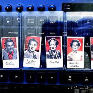 May include: Keyboard with clear plastic overlays featuring vintage RCA Victor recording artists: Dick Powell, Perry Como, Tony Martin, Peggy Wood, Dinah Shore, and Lisa Kirk. The keyboard is black with blue accents.