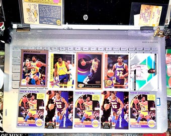 Könnte beinhalten: Eine Sammlung von Basketball-Sammelkarten mit Magic Johnson und Michael Jordan. Die Karten zeigen Actionaufnahmen der Spieler in ihren Lakers-Trikots, wobei die Nummer 32 deutlich sichtbar ist. Einige Karten haben das Lakers-Logo.