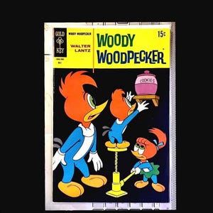 以下が含まれることがあります： ヴィンテージのウッディー・ウッドペッカーのコミック本の表紙。表紙には、ウッディー・ウッドペッカーと他の2羽のキツツキが漫画のスタイルで描かれています。背景は黒で、タイトルは黄色と緑色です。コミック本はゴールドキーからです。