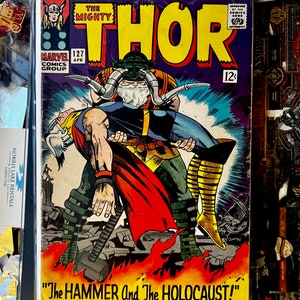 Può includere: Una copertina di fumetto vintage con Thor, il dio norreno del tuono, in un costume rosso e giallo. La copertina è intitolata "The Mighty Thor" e presenta il testo "The Hammer And The Holocaust!" in uno stendardo giallo in basso.