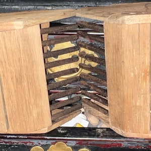 Könnte beinhalten: Eine Holzkiste mit einem Metallgitter im Inneren. Die Kiste ist aus hellbraunem Holz und hat ein schlichtes Design. Das Gitter besteht aus Metallstäben und ist leicht verrostet.
