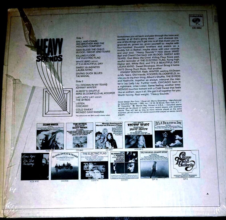 May include: The back cover of a Heavy Sounds vinyl record album featuring a tracklist, descriptive text, and small black and white thumbnail images of other Columbia record releases. The cover is white with black text and a torn plastic sleeve.