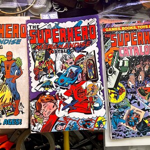 May include: Three vintage comic book covers featuring superhero merchandise catalogues. The covers feature colourful illustrations of popular superheroes such as Spider-Man, Hulk, and Superman. The text on the covers reads "The Superhero Merchandise Catalogue" and "Fun for All Ages!"