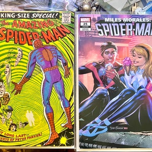 Op de afbeelding: Twee stripboeken met Spider-Man. De eerste is een King-Size Special editie van The Amazing Spider-Man met een groene en gele cover waarop Spider-Man in een rood en blauw pak te zien is. De tweede is een Miles Morales: Spider-Man stripboek met een rode, paarse en blauwe cover waarop Spider-Man en een vrouw in een wit en rood pak te zien zijn.