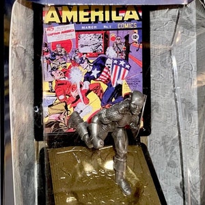 K&ouml;nnte beinhalten: Eine limitierte Feinzinnfigur von Captain America in Aktion. Die Figur wird vor dem Hintergrund eines Vintage-Covers von "America Comics" mit Captain America pr&auml;sentiert. Die Verpackung enth&auml;lt den Text "Limited Edition" und "Fine Pewter Figure".