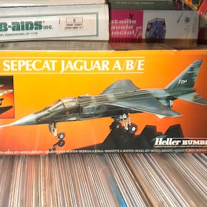May include: A 1/72 scale model kit of a Sepecat Jaguar A/B/E fighter jet. The box art features a detailed illustration of the aircraft in flight, with the words "Sepecat Jaguar A/B/E" and "Heller Humbrol" printed on the box.