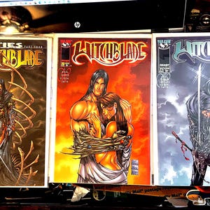 Puede incluir: Se muestran tres cómics de Witchblade. Las portadas presentan ilustraciones de personajes en acción, con una estética oscura y gótica. La primera portada muestra una figura con una capa oscura. La segunda portada representa a una pareja abrazándose. La tercera portada muestra una figura con una espada.