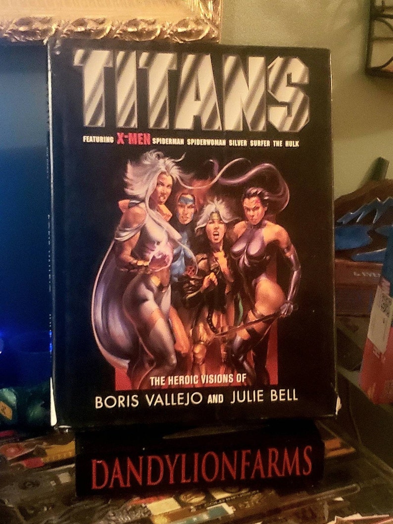 May include: A black and white comic book cover featuring the title "TITANS" with the words "FEATURING X-MEN SPIDERMAN SPIDERWOMAN SILVER SURFER THE HULK" and "THE HEROIC VISIONS OF BORIS VALLEJO AND JULIE BELL". The cover features a group of comic book characters, including Storm, Wolverine, and Jean Grey.