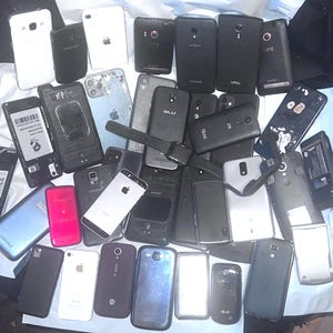 May include: A collection of various smartphones, including models from Samsung, Apple, and other brands. The phones are in various conditions, with some showing signs of wear and tear. The image includes a smartwatch.