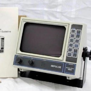 May include: An Impulse Micro-Trac 6800 marine electronic display unit with a gray casing, a dark screen, and a black control panel featuring buttons and knobs. The device includes a mounting bracket with side adjustment knobs and an instruction manual.