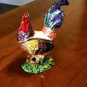 Handcrafted Enamel Hinged Rooster Trinket Box. Has rhinestone accents and a magnetic seal. In excellent condition. Approximately 3” tall.