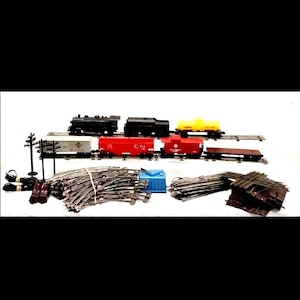 May include: A model train set featuring a black steam engine, various freight cars in red, yellow, and silver, and a brown flatbed car. Includes track pieces, a blue container, and a black telephone pole. The set is designed for model train enthusiasts.