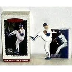 May include: A baseball-themed collectible figurine of a pitcher in a white uniform, mid-throw. The figurine is accompanied by a box and a card featuring similar imagery. The box has a red banner and text that reads "NEW COLLECTOR'S SERIES".