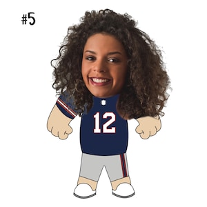 May include: A cartoon character with a woman's face wearing a blue jersey with the number 12 on it. The character has brown curly hair and is wearing grey shorts with blue stripes.