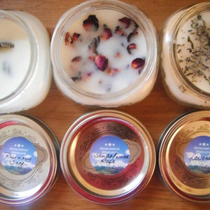 May include: Six glass jar candles with white wax. Some candles have dried flowers and herbs on top. The lids have labels that read "Rosemary Sage", "Sandalwood Rose", and "Lavender".