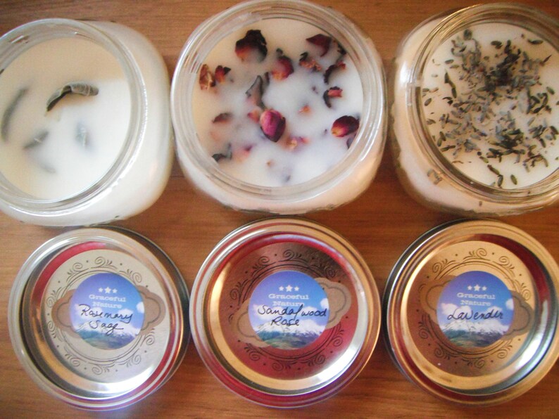 May include: Six glass jar candles with white wax. Some candles have dried flowers and herbs on top. The lids have labels that read "Rosemary Sage", "Sandalwood Rose", and "Lavender".