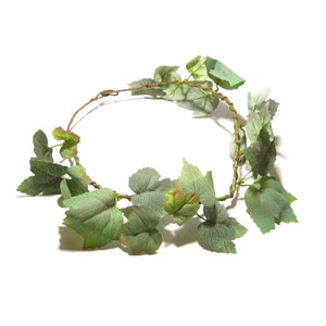 Könnte beinhalten: Ein grüner Weinrebenkranz mit Blättern, die in einem Kreis angeordnet sind. Der Kranz besteht aus künstlichen Blättern und Ranken.