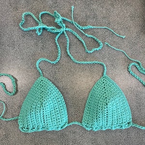 May include: A teal crochet bikini top with adjustable straps.