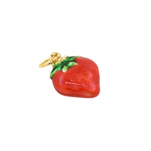 Puede incluir: Un amuleto de oro en forma de fresa roja con hojas verdes.