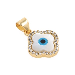 May include: Gold pendant with a white shell and blue evil eye charm surrounded by clear cubic zirconia stones.