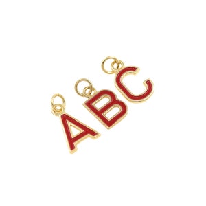 May include: Three gold-colored metal charms in the shape of the letters A, B, and C. The letters are filled with red enamel.