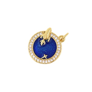 May include: Gold-toned pendant with a blue enamel center featuring a rocket ship and star design. The pendant is round, with a border of small, clear crystals. The rocket is gold, and the background is a deep blue.