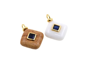 May include: Two square pendants with gold loops. One is a light brown stone with a dark blue square gem. The other is white with a dark blue square gem. Both have gold frames.