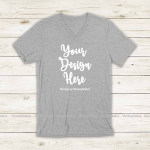 May include: Gray V-neck t-shirt mockup with the text "Your Design Here" and "Mockup by MockupStation" printed on the front.