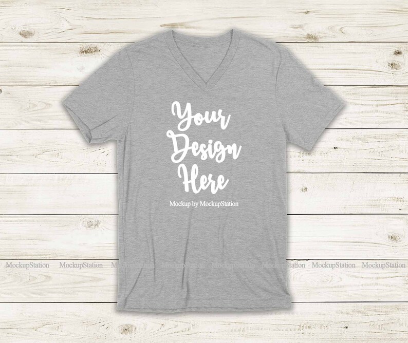 May include: Gray V-neck t-shirt mockup with the text "Your Design Here" and "Mockup by MockupStation" printed on the front.