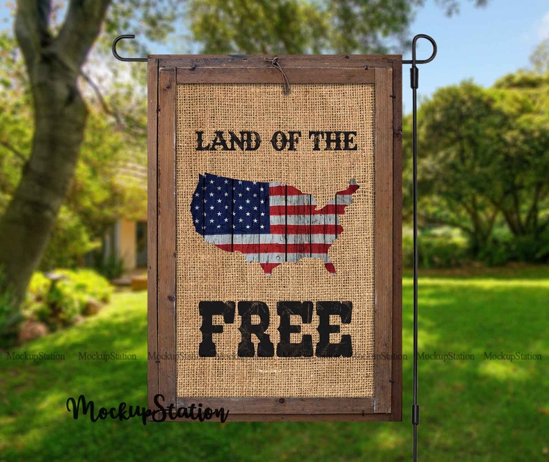Pode incluir: Uma bandeira de jardim de juta com uma moldura de madeira. A bandeira apresenta uma bandeira americana vermelha, branca e azul em forma dos Estados Unidos. O texto "Land of the Free" est&aacute; impresso em preto na bandeira.