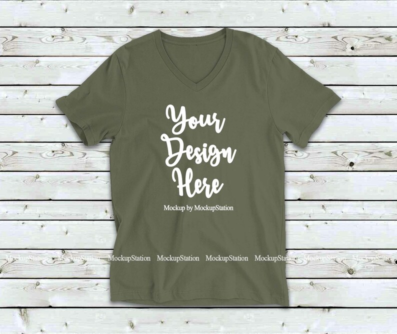 May include: A plain olive green v-neck t-shirt with short sleeves. The shirt has the text "Your Design Here" in white on the front. Mockup by MockupStation.
