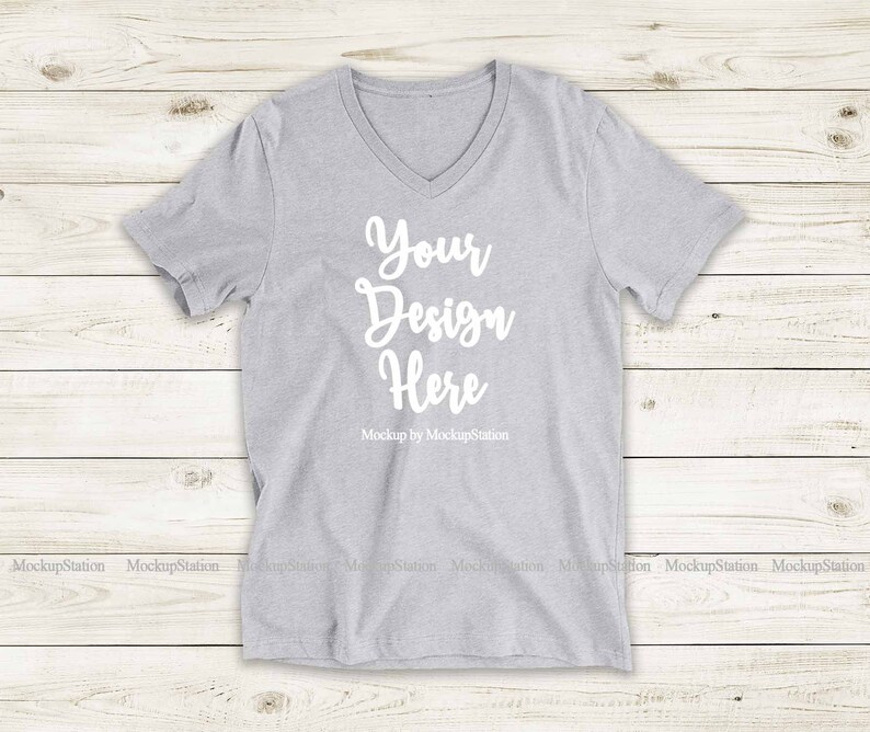 May include: A gray V-neck t-shirt with the text "Your Design Here" and "Mockup by MockupStation" printed on the front.