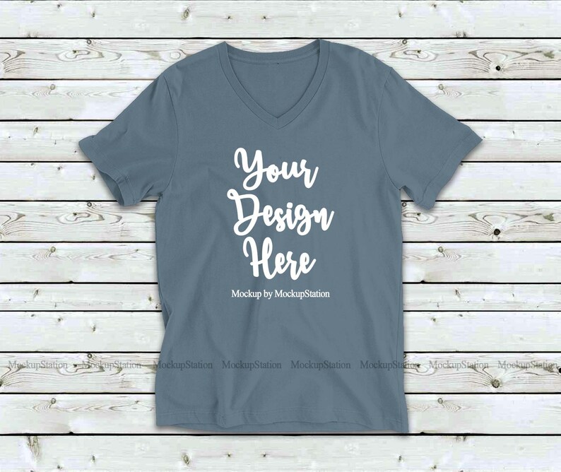 May include: A plain, light blue v-neck t-shirt mockup on a wood background. The text "Your Design Here" is printed on the shirt. "Mockup by MockupStation" is printed below the text.
