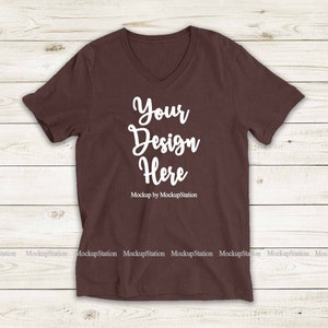 May include: A brown V-neck t-shirt with the text "Your Design Here" and "Mockup by MockupStation" printed on the front.