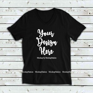 May include: Black v-neck t-shirt mockup with the text "Your Design Here" on a white wooden background.